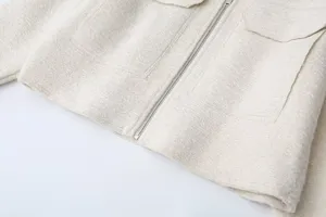 Close-up detail of women's textured tweed jacket with front zipper and pocket design.