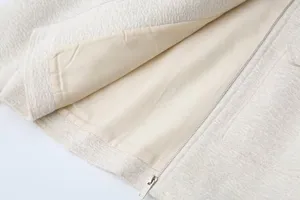White textured tweed jacket inner lining and metal zipper detail view, stylish apparel.