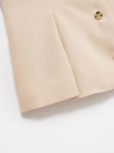 Detailed view of women's beige vest fabric and golden button, premium sewing texture.