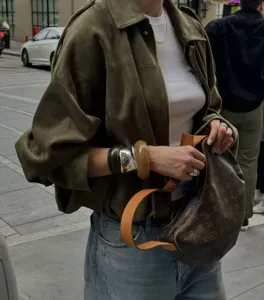Olive green suede jacket close-up, batwing sleeve design, stylish street style apparel.