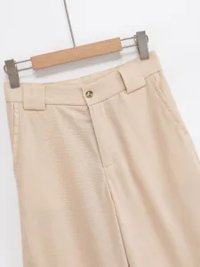 Detailed view of women's beige wide-leg trousers waist design with button and belt loops.