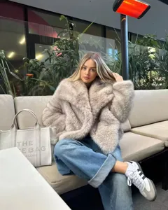 Faux fur coat detail showing soft plush texture and cozy lifestyle styling in indoor setting.