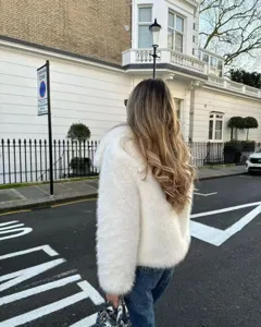 Outdoor detail shot of a soft faux fur hooded jacket styled in a casual street look.