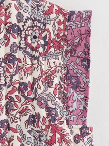 Close-up of vintage ethnic quilted cotton vest fabric with retro floral print and stitching.