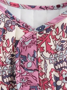Detailed close-up of retro floral quilted vest fabric, showing fine stitching and pink trim.