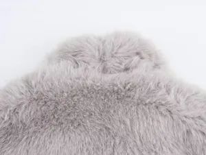 Close-up detail of grey faux fur coat fabric, soft fluffy texture for winter women apparel.