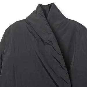 Primer plano detalle del cuello de chaqueta acolchada estilo kimono negro, tela minimal chic.