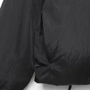 Vista detallada del tejido de la chaqueta acolchada negra arrugada con finas costuras y textura.