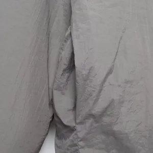 Detalle de tela de chaqueta acolchada gris, con textura arrugada y costuras finas.