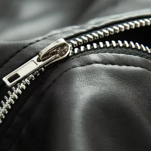 Nahaufnahme der Details einer schwarzen Damen-Lederjacke mit robustem silbernem Metallreißverschluss.