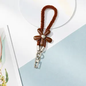 Cordon lanière de téléphone fleur en cuir peluche marron avec fermoirs métalliques.
