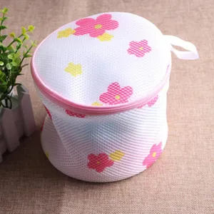 Cylindrical mesh laundry bag with pink floral pattern, zipper closure, and hanging loop.