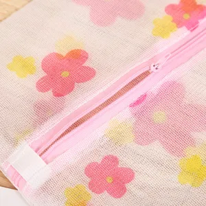 Vue détaillée du sac à linge en résille à fleurs roses, texture fine et fermeture.