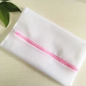 Vue détaillée d'un sac de lavage en filet fin blanc avec fermeture éclair rose pour sous-vêtements.