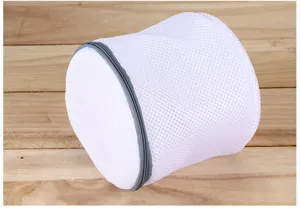 Détail de sac à linge en filet blanc cylindrique avec fermeture éclair grise bois.
