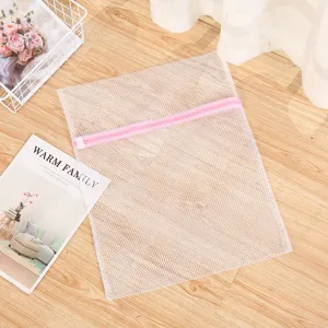 Sac à linge en maille fine avec fermeture éclair rose pour protéger les vêtements délicats.