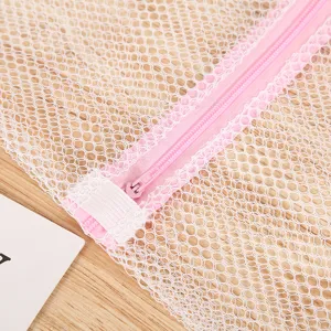 Gros plan détaillé du sac de lavage en filet blanc avec fermeture éclair rose et protection.