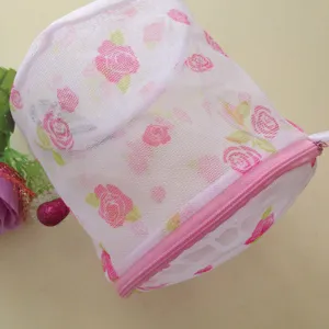 Detailed close-up of a white mesh laundry bag with pink floral print and zipper closure.