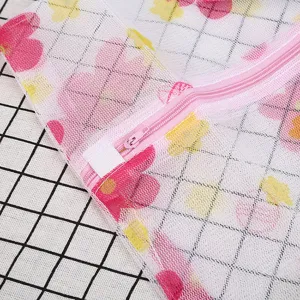 Vue détaillée du grand sac à linge en filet imprimé avec fermeture éclair rose et fleurs.