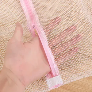 Sac à linge en filet blanc avec fermeture éclair rose, pochette de lavage durable pour vêtements.