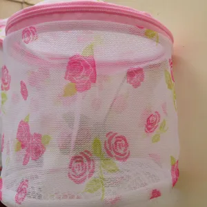 Detailed view of cylindrical mesh laundry bag featuring charming pink rose print and secure zipper.