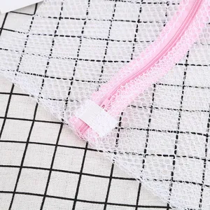 Detalle de cerca de bolsa de lavandería de malla blanca con cremallera rosa y tejido fino.