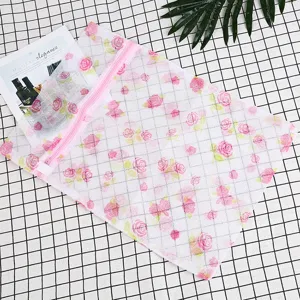 Gros plan detaille du sac a linge en maille imprime avec motif de roses et fermeture eclair.