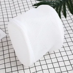 Detailed shot of a white cylinder mesh laundry bag with zipper on a grid background.