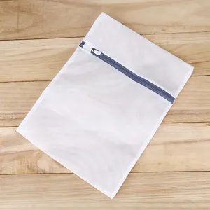White mesh laundry wash bag with blue zipper flat laid on wooden background for clothes.