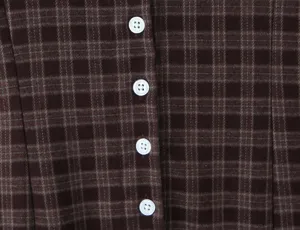 Detail de tissu de robe carreaux marron vintage gros plan avec boutons blancs retro