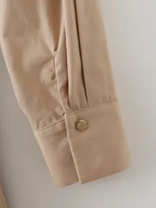 Primo piano del polsino a manica lunga elegante con bottone dorato per abito donna.