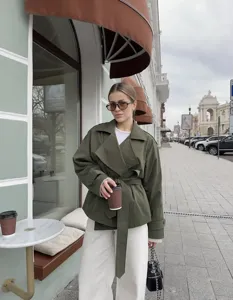 Detail view of the stylish olive green short trench coat featuring a chic lapel and belt.