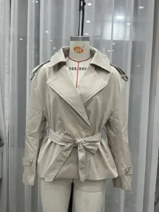 Detail view of women's short beige trench coat with lapel collar, double-breasted and belt.