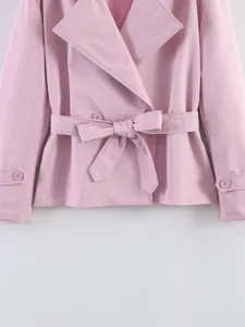 Close-up view of a pink short trench coat featuring a lapel collar and a tied waist belt.
