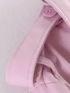 Pink trench coat detail shot, featuring neat stitching, lapel collar, and matching button.
