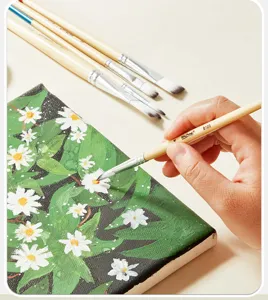Close-up of artist paintbrush in hand painting canvas with soft nylon bristles and wooden handle.