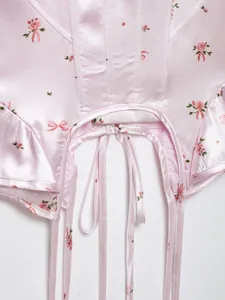 Pink satin floral corset top detail showing delicate rose print, bow ties, and bone structure.