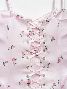 Detail view of a pink satin floral corset top with lace-up ribbon back and metal eyelets.