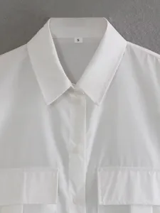 Detailed close-up of a classic white long-sleeve button-up shirt collar and double pockets.