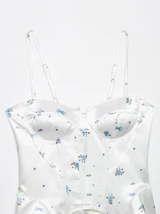 Close-up detail of white satin floral bustier corset top with delicate straps and blue print.