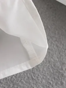 White shirt hem and stitching detail close-up, showing fine sewing craftsmanship and fabric.