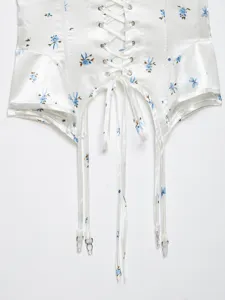 Detail view of a white floral satin corset top featuring front lace-up and garter straps.