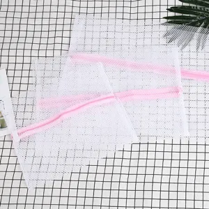 Vista detallada de bolsas de lavado de malla blanca con cremalleras rosas para prendas delicadas.