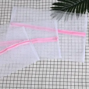 Bolsas de malla blanca para lavandería con cremallera rosa para proteger la ropa delicada.