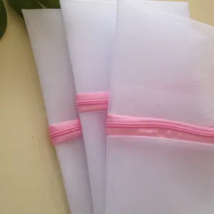 White mesh laundry bags set with pink zippers for delicate clothes, underwear and bras washing.