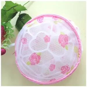 Round mesh laundry bag with pink zipper and floral print for delicate washing and bra protection.