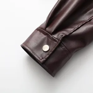 Nahaufnahme der langärmligen Manschette einer dunkelbraunen Kunstlederjacke mit Druckknopf.