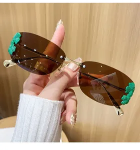 Vue détaillée de lunettes de soleil tendance en métal sans monture avec décors de trèfle.