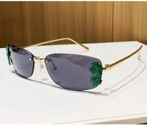 Lunettes de soleil carrées tendance pour femme avec trèfle vert et monture en métal.
