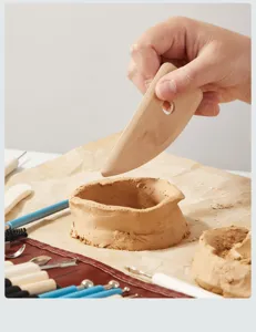 Detalle de la herramienta de modelado de madera mostrando el proceso de arcilla cerámica.
